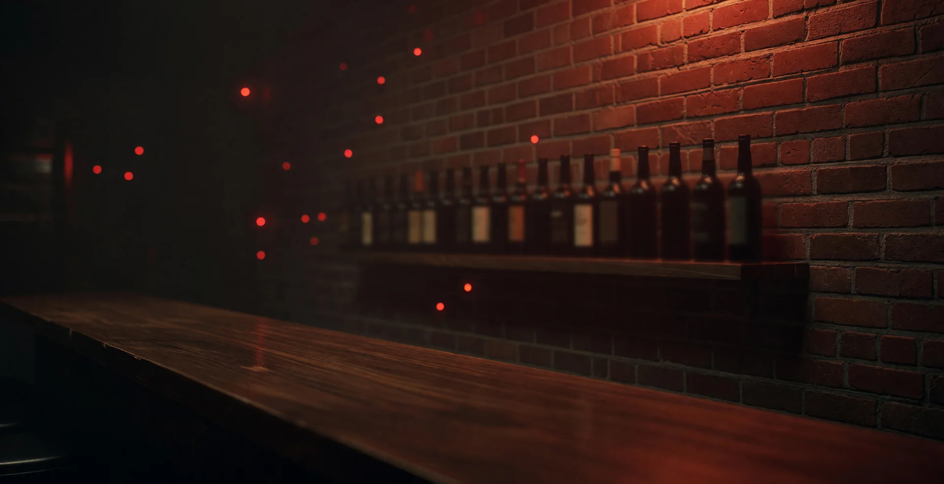 The back wall of a wood home bar at night, a red and amber sign glow washing over the brick behind a shelf of bottles